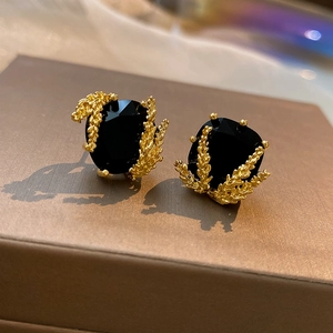 Vue macro de boucles d'oreilles carrées plaquées or avec pierres noires facettées et détails