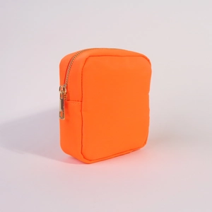 Detail view of square orange nylon pouch featuring a durable golden zipper closure