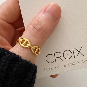 Macro shot of a golden chain-link ring with an anchor design on a finger