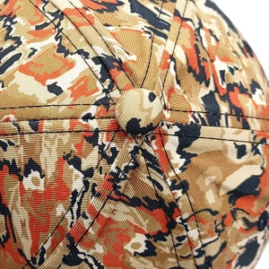 Macro shot of six-panel crown stitching and orange tiger camo twill fabric on baseball cap