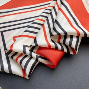 Detailed view of folded silk scarf with red, black, and white geometric stripe pattern