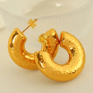 18K gold plated hollow C-shaped hoop earrings with hammered texture on leather background