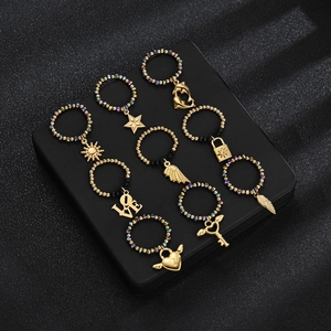Set of 8 elastic beaded rings with assorted gold-tone charms on a black display box