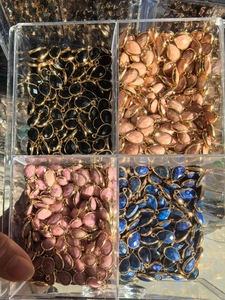 Bulk display of teardrop natural gemstone pendants with gold plating in a clear acrylic box