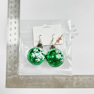 Christmas bulb earrings with white snowflakes shown next to a ruler for size reference