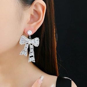 Close-up detail of silver bow earrings set with sparkling cubic zirconia on model