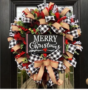 Close-up of Merry Christmas sign on festive wreath with red berries and buffalo plaid bow