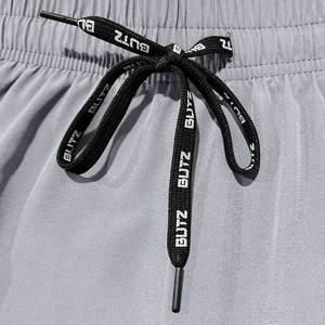Macro detail of adjustable black drawstring with white text on gray textured shorts