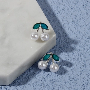 Detail of cherry stud earrings with white pearl fruits and green enamel leaves