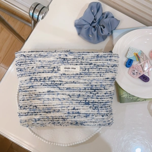Close-up of blue and white tweed makeup bag featuring simple wish woven label detail