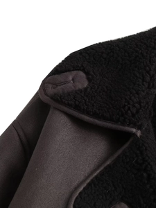 Détail macro des coutures en peau lainée noire et cuir sur le col et l'épaule