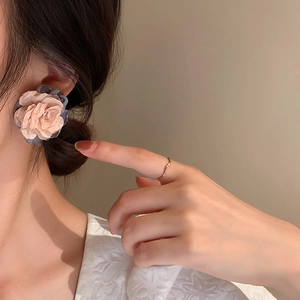 Detailed view of layered fabric flower earrings in dusty pink and smoky blue colors