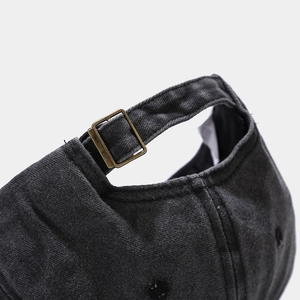 Detail of adjustable metal buckle and washed denim fabric on dark grey baseball cap