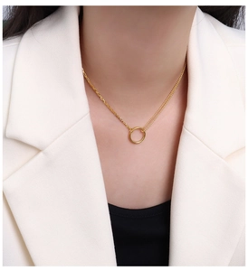Detail of asymmetrical double-chain choker with gold circular pendant on a female model