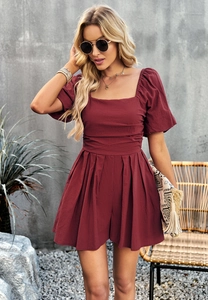 Detail of square neck and puff sleeves on a burgundy jumpsuit worn by a model