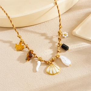 Detail of woven rope necklace with gold maple leaf, tiger eye stone, and baroque pearl