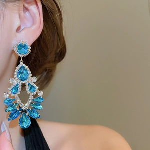 Detail of luxury teardrop fringe earrings with blue crystals and sparkling gold setting
