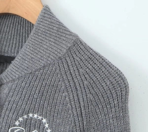 Detail of dark grey rib-knit sweater featuring white star embroidery on the chest