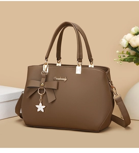Detail of a brown leather handbag with a bow decoration and a white star charm