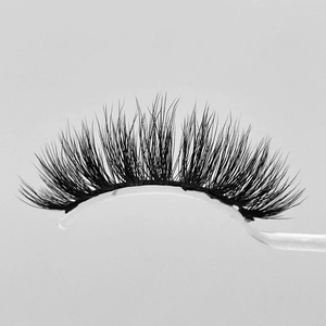 Short faux mink eyelashes with black synthetic fibers on a white curved holder