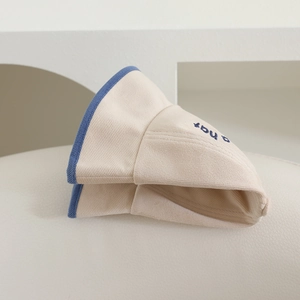 Détail d'un chapeau bob en coton crème avec broderie bleue et bordure contrastée