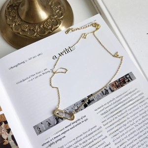 925 silver gold-plated safety pin necklace with pavé zircons on an art book background