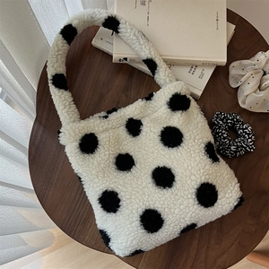 Détail de la texture pelucheuse du sac en laine d'agneau blanche à pois noirs