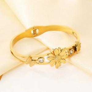 Gros plan du bracelet tournesol doré avec papillon et zircon sur un tissu en soie beige