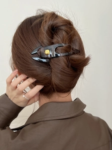 Detail view of large tortoiseshell hair claw clip with golden fashion lettering on model