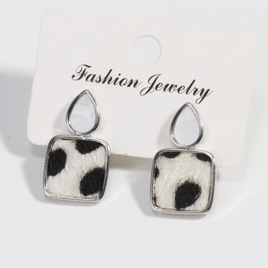 Detail of silver drop earrings with white stone and black spotted faux fur texture