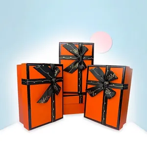 Three-piece set of orange gift boxes with luxury black ribbons and gold happy font