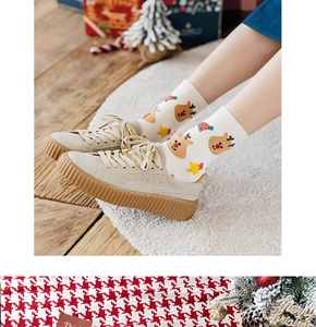 Detail of beige Christmas socks with deer patterns worn with khaki suede sneakers