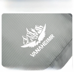 Close-up of grey ripstop fabric and VANAHEIMR outdoor logo on a foldable backpack