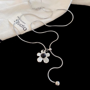 Detail of silver five-petal flower necklace with black stone on a dark background