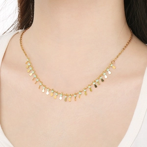 Detail of gold tassel necklace featuring light green beads and water drop pendants