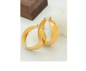 Close-up of wide 18K gold plated stainless steel hoop earrings on a marble surface