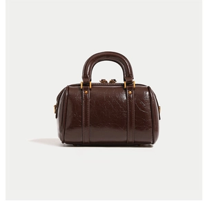 Close-up of dark brown glossy leather texture and gold hardware on Boston bag