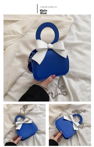 Detail view of Klein blue mini handbag with white bow decoration and silver chain strap