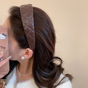 Close-up of a dark brown quilted leather headband worn by a model for a stylish look