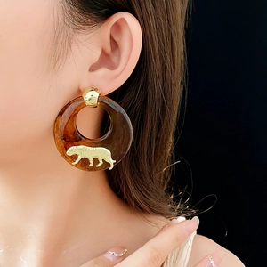 Detail of amber resin hoop earring with a golden leopard relief and stud closure