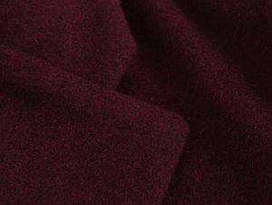 Macro shot of dark red wool fabric showing fine fiber texture and soft shadows on the surface