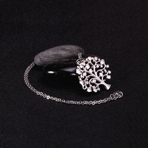 Macro view of silver tree of life pendant on dark pebbles with stainless steel chain