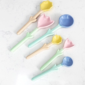 Flat lay of six floral ceramic spoons with colorful tulip-shaped heads on marble