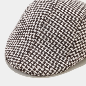 Detailed macro view of houndstooth wool fabric texture and stitching on winter newsboy cap
