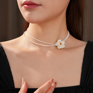 Close-up of double-layer beaded necklace featuring a white woven camellia flower pendant