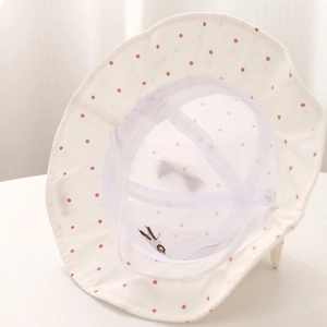 Detail view of breathable white mesh lining and pink polka dot pattern on baby sun hat