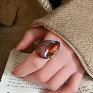 Vue détaillée d'une grande bague en résine ambrée avec bordure dorée sur un index chic
