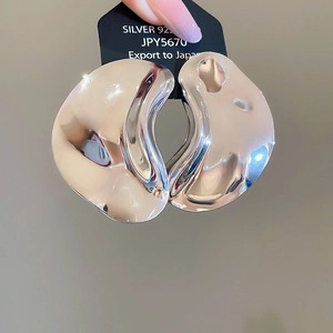 Macro shot of silver 925 irregular wavy earrings with a high-polished mirror finish