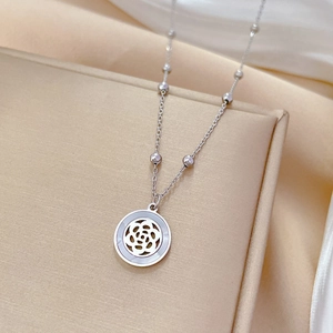 Detail of silver titanium necklace with camellia flower shell pendant on a gift box