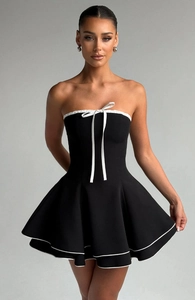Detail view of contrast piping and white ribbon bow on a black strapless dress